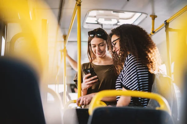 Two Cheerful Pretty Young Women Standing Bus Looking Phone — Stock Photo, Image