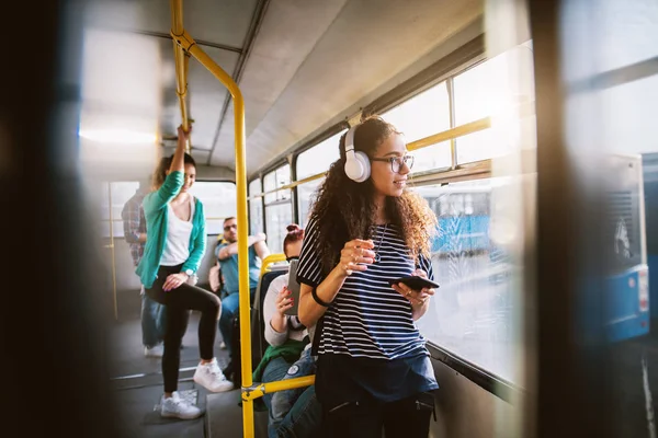 young beautiful woman listening to music on headphones in bus