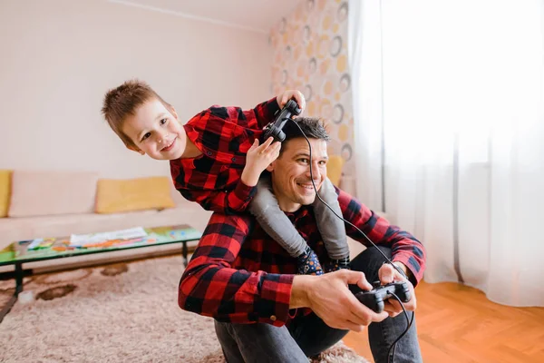 欢快兴奋的父亲和小儿子在红衬衫玩游戏机与游戏板 — 图库照片