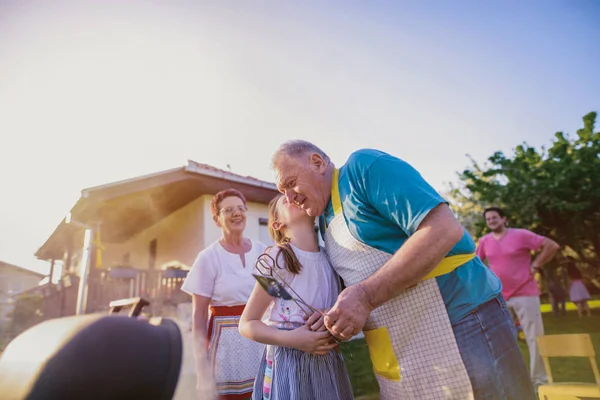 Дівчина Цілує Дідуся Готуючи Грилі Відкритому Повітрі — стокове фото