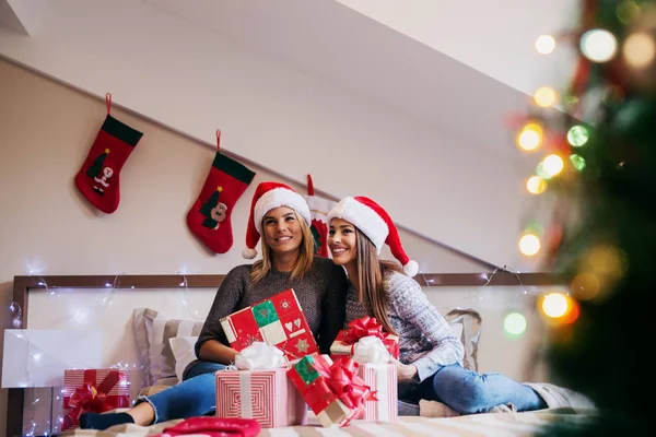 Duas Amigas Felizes Usando Chapéus Papai Noel Comemorando Natal Casa — Fotografia de Stock