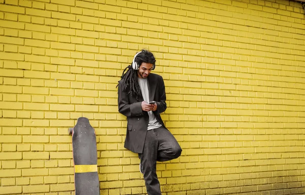 Jonge Schattige Hipster Dreadlocks Man Leunde Gele Muur Luisteren Muziek — Stockfoto