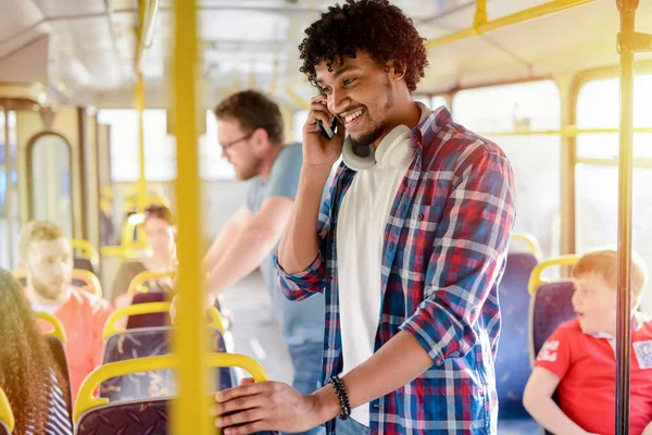 かわいい若いアフロアメリカンがバスに立ち 電話で話しています 笑顔と彼の仕事への旅 — ストック写真