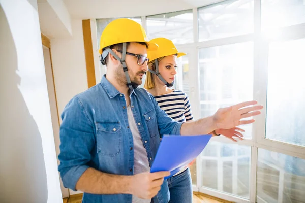 Two Focused Young Architects Helmets Heads Looking Projects Shoving Wall — Stok fotoğraf