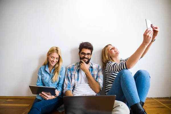 Imagen Los Jóvenes Estudiantes Árbol Sentados Suelo Sosteniendo Aparatos Mirando — Foto de Stock