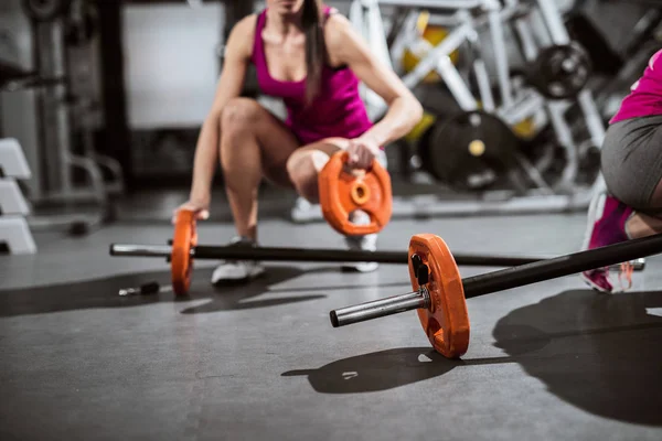 Women setting weights for lifting. Focus on weights.