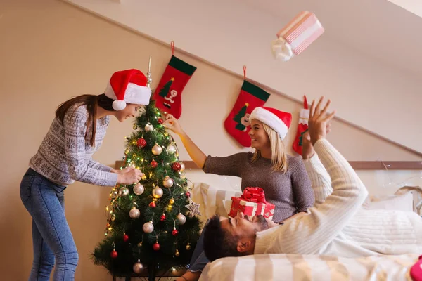 快乐的朋友戴着圣诞帽享受假日装饰圣诞树和玩礼物 — 图库照片
