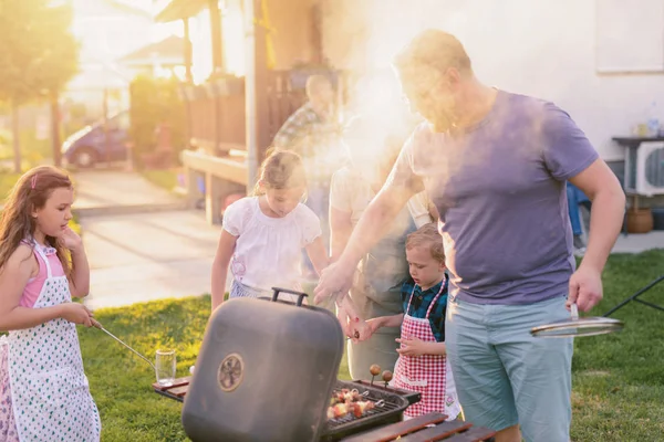 cheerful family cooking with outdoor grill at backyard, happy family barbecue