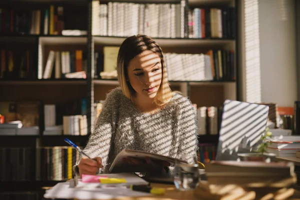 Menina Bonito Jovem Escola Sentado Biblioteca Tomar Notas Enquanto Olha — Fotografia de Stock