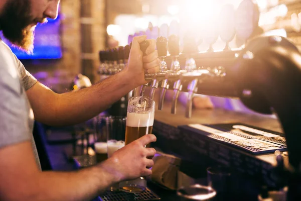 stock image Close up of bartender pouring beer into glass. Pub interior.