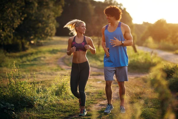 Young fit motivated couple jogging early in the morning. Happy, strong, good looking couple running outside.