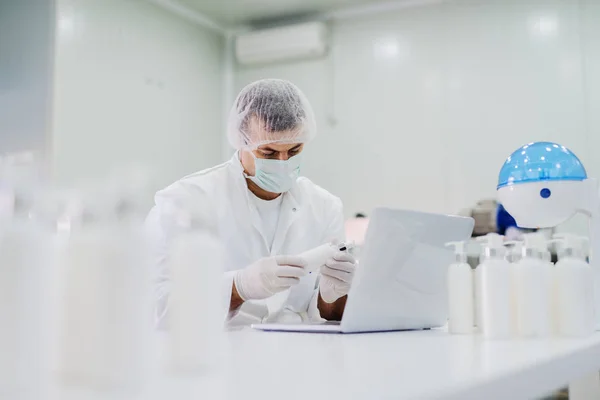 Imagem Jovem Roupas Estéreis Sentado Laboratório Brilhante Verificando Qualidade Dos — Fotografia de Stock