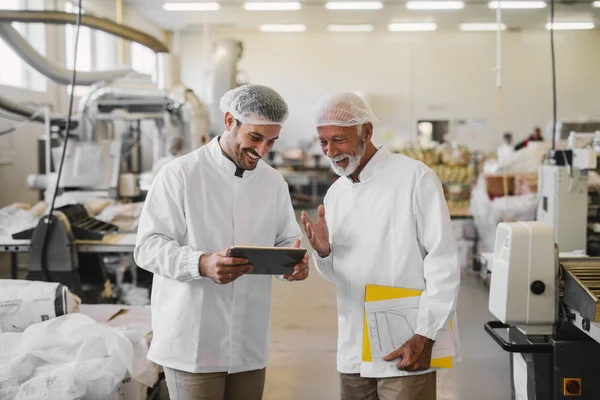 Two Cheerful Male Colleagues Sterile Clothes Standing Food Factory Looking — Stock Photo, Image