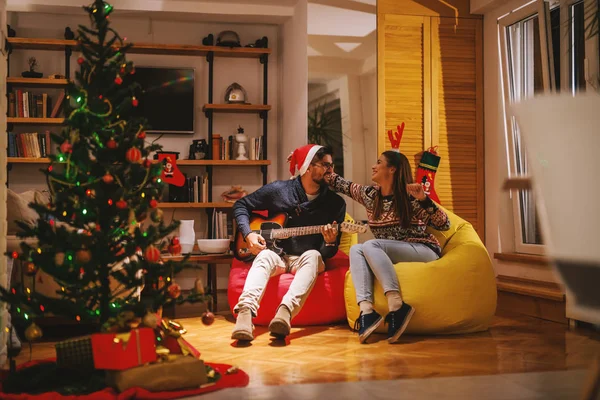 남자가 친구에 기타를 연주입니다 산타의 크리스마스 트리와 크리스마스 — 스톡 사진