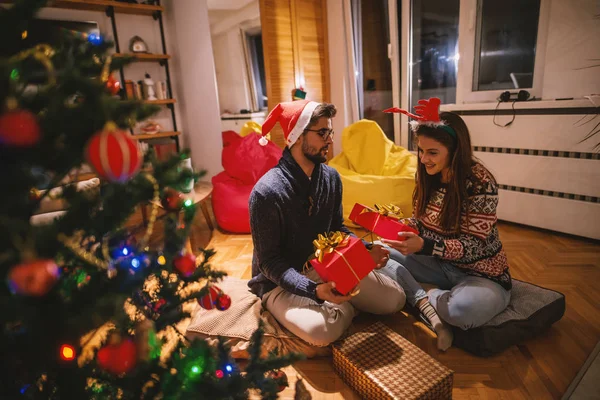 Paar Tauscht Weihnachtsgeschenke Während Auf Dem Boden Sitzt Vordergrund Weihnachtsbaum — Stockfoto