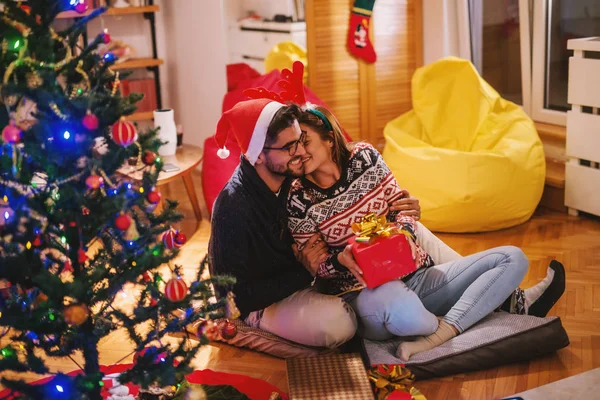 Glückliche Frau Bekommt Weihnachtsgeschenk Paar Auf Dem Boden Sitzend Daneben — Stockfoto