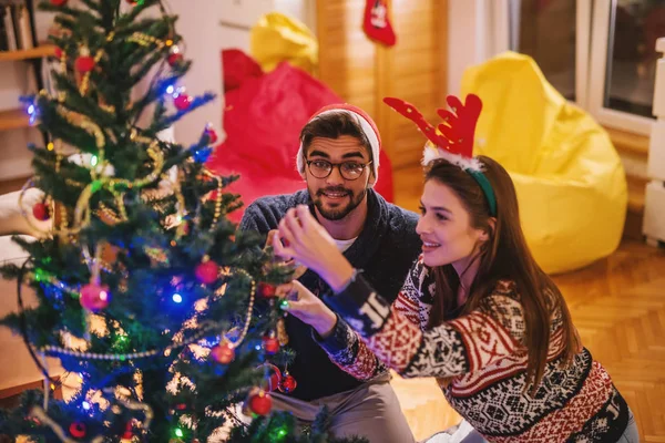 Paar Schmückt Weihnachtsbaum Auf Dem Kopf Weihnachtsmann Hut Und Rentier — Stockfoto