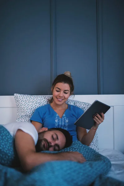 タブレットと寝ている彼氏をしている女の人 — ストック写真