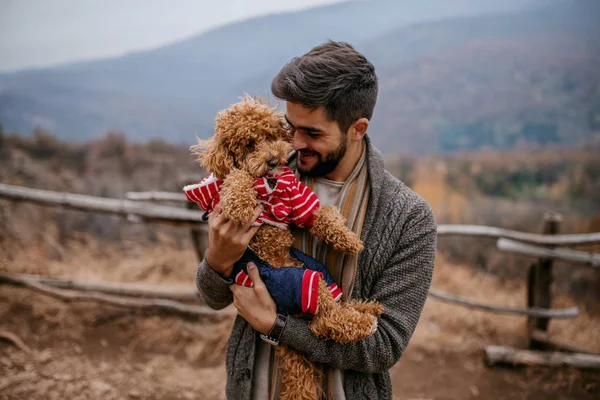 男子站在户外抱着狗 秋天的时间 在背景山 — 图库照片