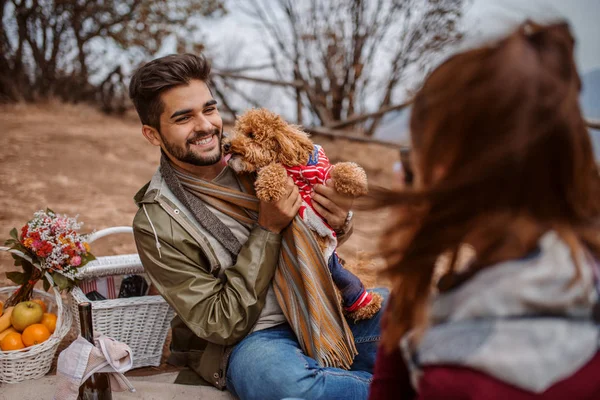 女性は彼女の彼氏とピクニックで毛布の上に座っている間の犬の写真を撮影 秋の時間 — ストック写真