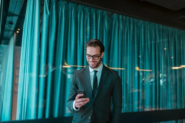 Uomo Affari Sorridente Piedi Fronte Alla Sala Conferenze Utilizzando Smartphone — Foto Stock