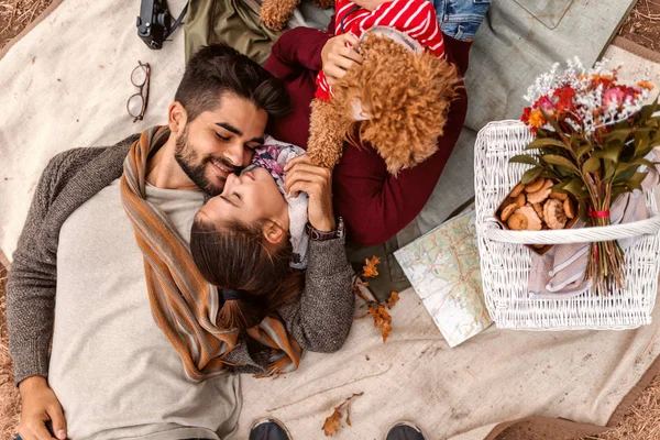 野餐时 一对夫妇的最高视野躺在毯子上 抱着狗的女人就在他们的篮子旁边秋季时间 — 图库照片