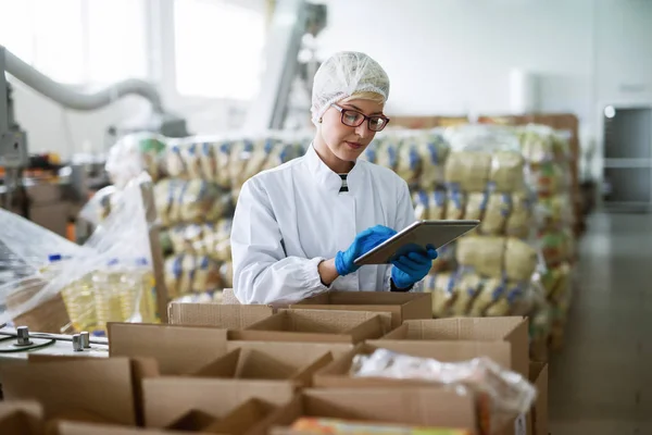 Lavoratrice Che Utilizza Tablet Controllare Caselle Mentre Piedi Fabbrica Alimenti — Foto Stock