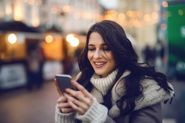 寒さに通りにスマート フォンを使用して 笑顔の若い美しい白人女性のクローズ アップ — ストック写真