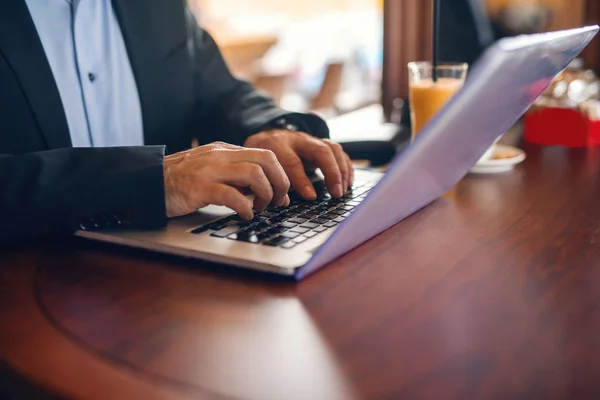 关闭在键盘上打字的人 在办公桌上的笔记本电脑 果汁咖啡 咖啡厅内饰 — 图库照片