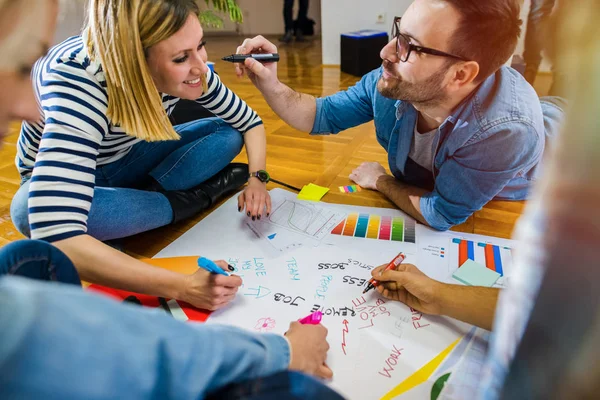 Grupo Jóvenes Diseñadores Creativos Sentados Suelo Tomando Notas Papel Grande —  Fotos de Stock