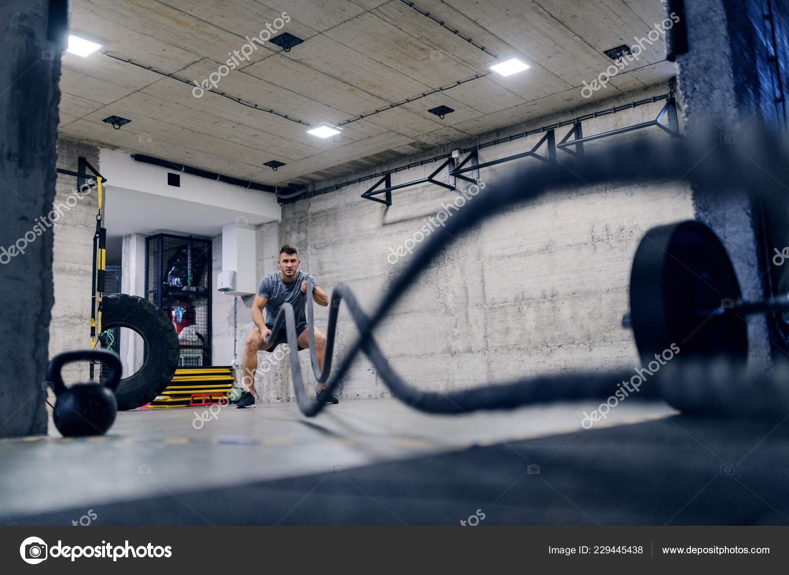 Young Caucasian Man Sportswear Exercising Battle Ropes Gym