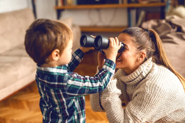 母亲和儿子在公寓里玩 孩子把女人的眼睛双筒望远镜 — 图库照片