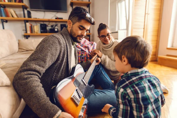 Pai Tocando Guitarra Elétrica Sentado Chão Enquanto Sua Família Olhando — Fotografia de Stock