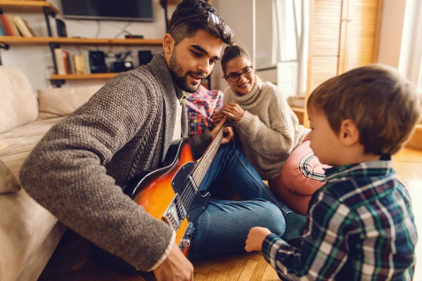 Pai Tocando Guitarra Elétrica Sentado Chão Enquanto Sua Família Olhando — Fotografia de Stock