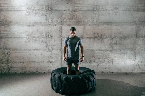 Caucasian man preparing to lift tire on his cross-fit training. You don't stop when you tired, you stop when you're done.