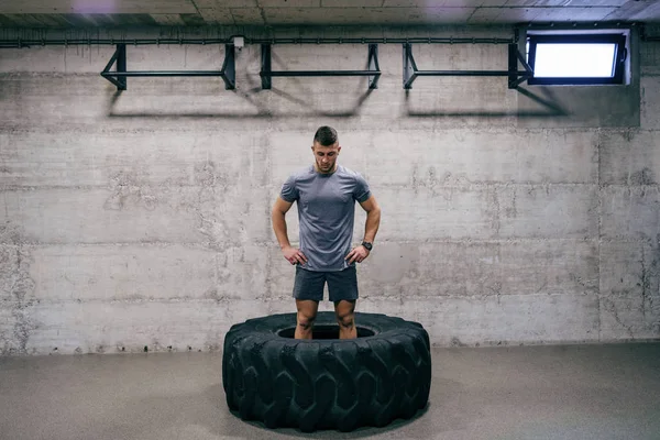 Caucasian man preparing to lift tire on his cross-fit training. Hands on hips. Your limit is you.