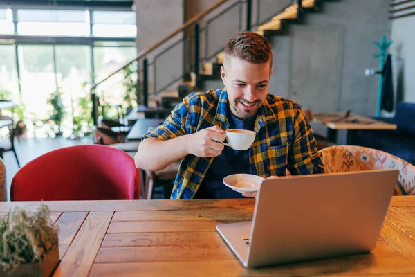 Sonriente Caucásico Freelancer Masculino Bebiendo Café Mirando Computadora Portátil Mientras —  Fotos de Stock