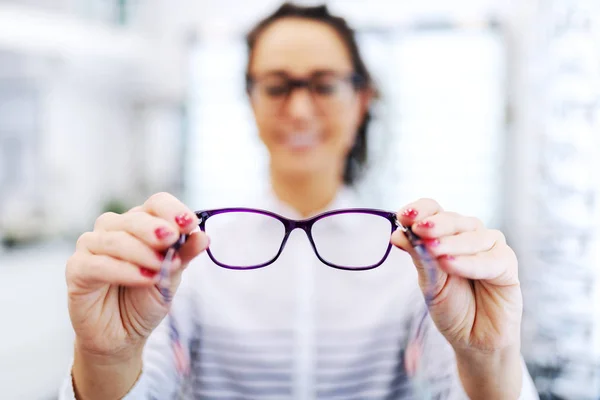 眼镜店的女人拿着她想买的眼镜 选择关注眼镜 — 图库照片