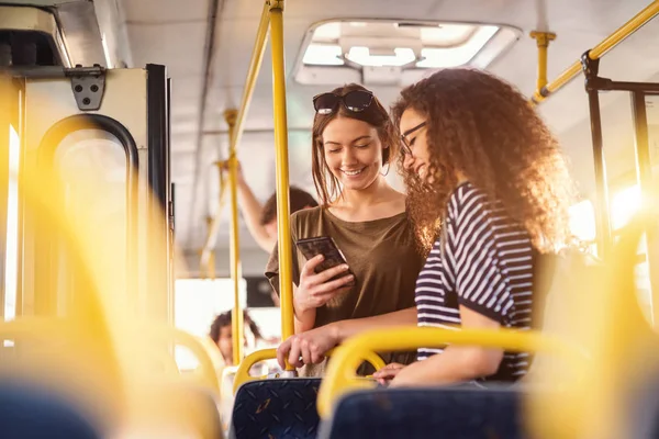 陽気なかなり若い女性がバスの中で立っていると 携帯電話を見て — ストック写真