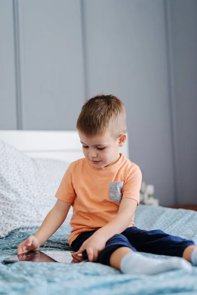 Маленький Мальчик Сидит Кровати Пижаме Смотрит Мультики Планшете Перед Сном — стоковое фото