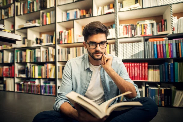 Schattige Lachende Hipster Man Zittend Vloer Van Een Bibliotheek Kijkend — Stockfoto