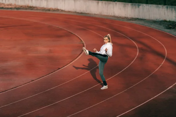 Mujer Rubia Sonriente Ropa Deportiva Pateando Aire Mientras Está Pie — Foto de Stock