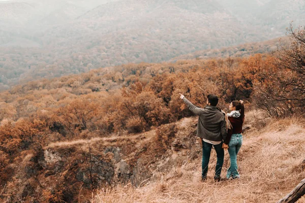 幸せなカップルが手を繋いでいると美しい景色を見てします 男は何かを指しています 秋の時間バックアップになって — ストック写真