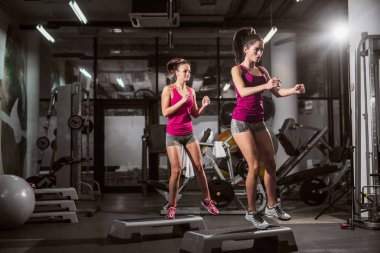 Two women exercising on steps in gym.Healthy lifestyle concept. clipart