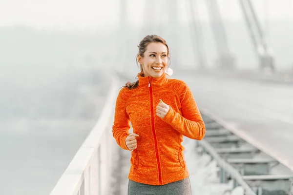 快乐的高加索妇女穿着运动服 在冬天在桥上跑马尾 冬季健身理念 — 图库照片