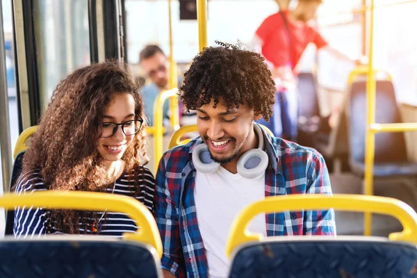 Молода Мультикультурна Пара Дивиться Вниз Посміхається Сидячи Їздячи Міському Автобусі — стокове фото