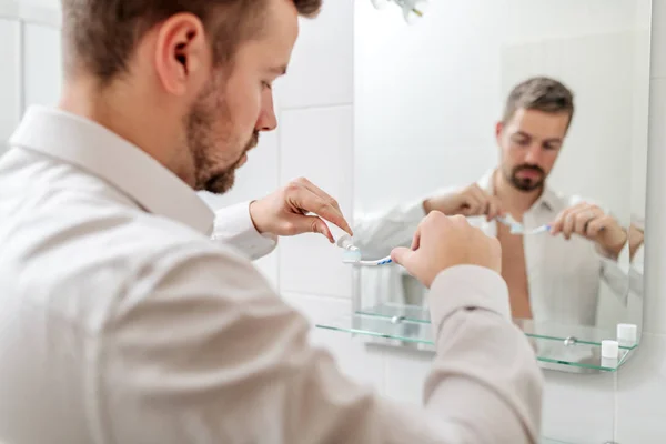 Forretningsmann Som Legger Tannkrem Børsten Mens Han Står Foran Speilet – stockfoto