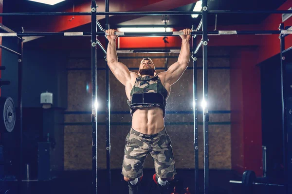 肌肉强大的高加索健美运动员做拉 Ups 与重量背心上 健身房内饰 夜间锻炼的概念 — 图库照片
