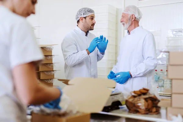 Due Lavoratori Uniformi Bianche Sterili Che Imballano Biscotti Parlano Piedi — Foto Stock