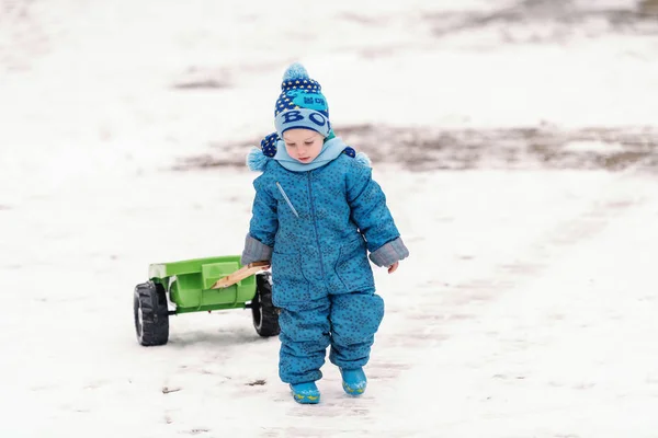 Lindo Niño Vestido Con Ropa Azul Invierno Arrastrando Juguete Del —  Fotos de Stock